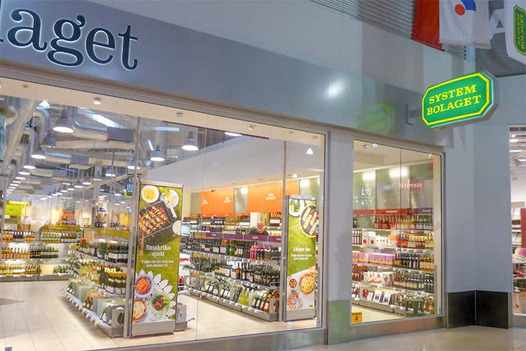 Vista externa de uma loja Systembolaget na Suécia, mostrando sua entrada e interior.