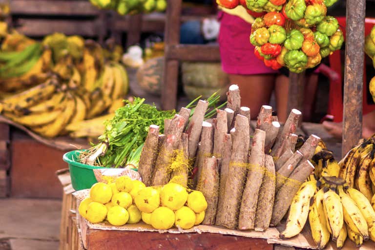 A vibrant market stall in Cartagena displaying bananas, citrus fruits, and cassava.