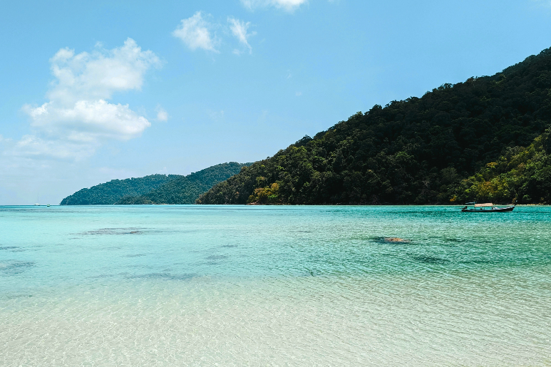 Спокойный пляж с прозрачной бирюзовой водой и холмами.