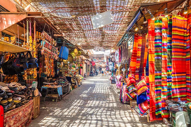 Una vibrante calle del mercado de Marrakech con coloridos tejidos y mercancías.