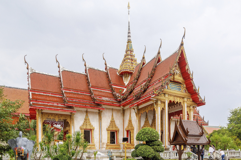 Храм Ват-Чалонг на Пхукете — с затейливой красно‑золотой архитектурой — под пасмурным небом.