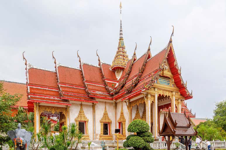 Храм Ват-Чалонг на Пхукете — с затейливой красно‑золотой архитектурой — под пасмурным небом.