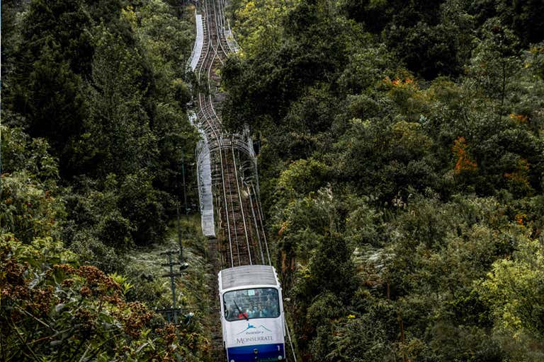 The Monserrate funicular ascending through lush green forested hills in Bogotá.