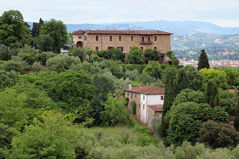 A scenic view of Villa Bardini surrounded by lush greenery and hills.