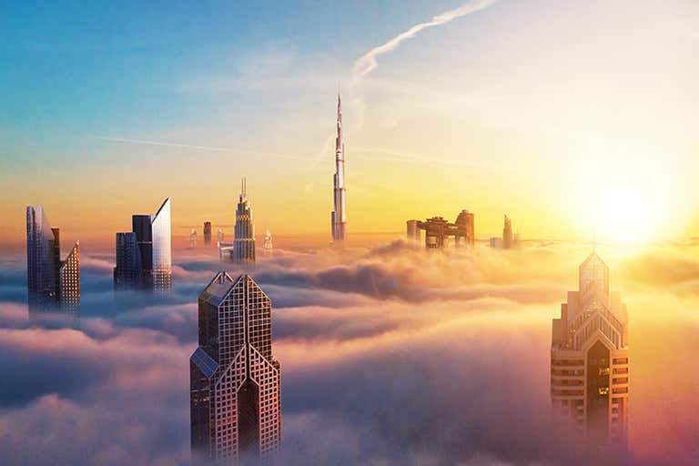 De skyline van Dubai met wolkenkrabbers die tevoorschijn komen bij zonsondergang.