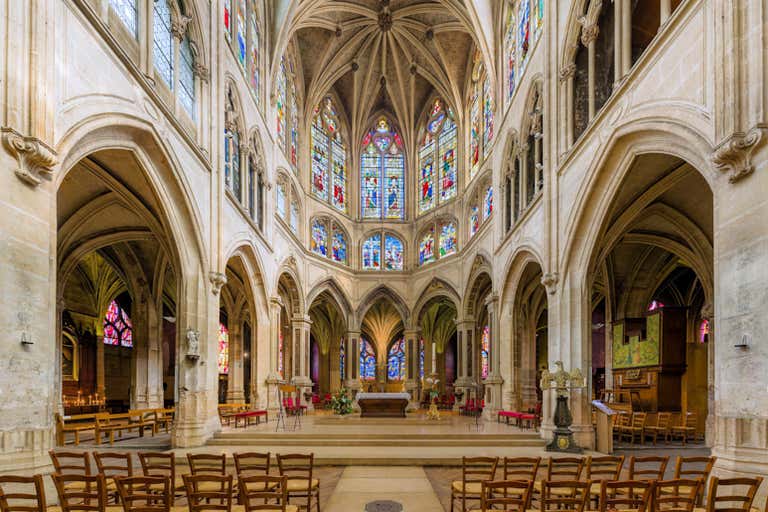 Interior of Saint-Séverin with soaring Gothic arches, colorful stained glass windows and unique palm tree-like columns