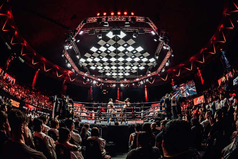 Modern Muay Thai boxing arena with dramatic lighting and packed crowd, showcasing Thailand's national sport