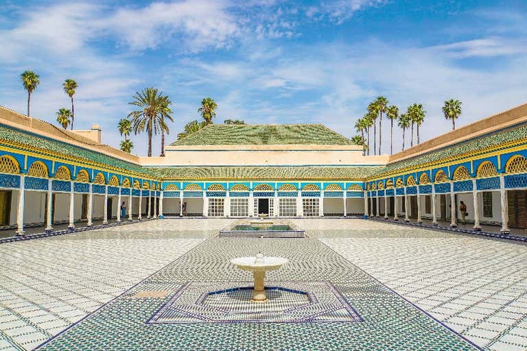 Un patio con una fuente en el Palacio Bahía, Marrakech, bajo un cielo azul.