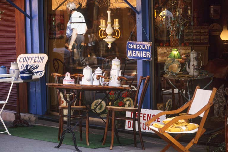 Charming antique shop with vintage signs, porcelain teapots, and eclectic decor outside a quaint Parisian street.