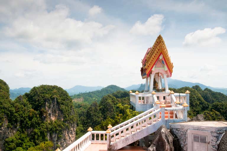 Ornate Buddhist temple pavilion with golden spires overlooking dramatic mountain landscape in Krabi, a must-visit spiritual site