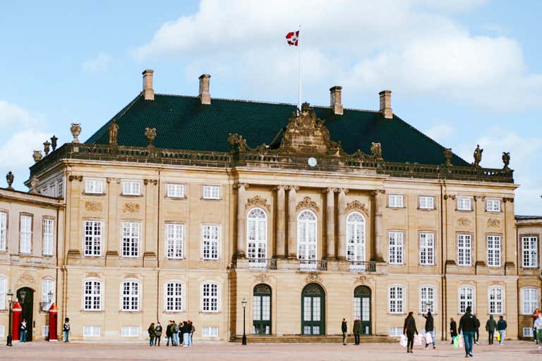 Elegant Rococo facade of Amalienborg Palace with Danish flag flying, Copenhagen's royal residence and essential Danish landmark