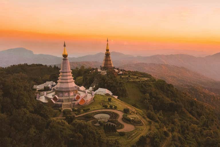 Two royal pagodas on Doi Inthanon mountain at sunset, surrounded by misty mountains and manicured gardens