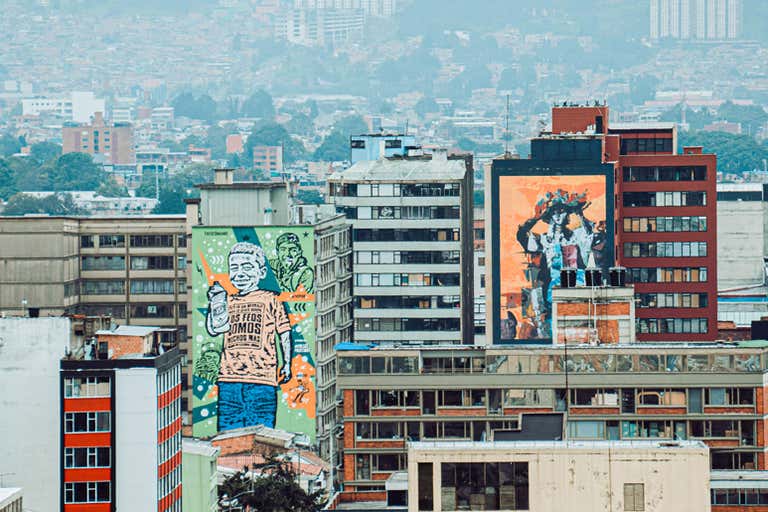 Colorful murals on Bogotá’s buildings showcasing vibrant street art against an urban backdrop.