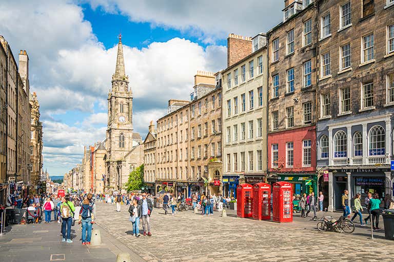 A bustling street in Edinburgh with historic buildings and red phone booths.