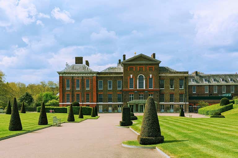 Kensington Palace with manicured gardens and a cloudy sky.
