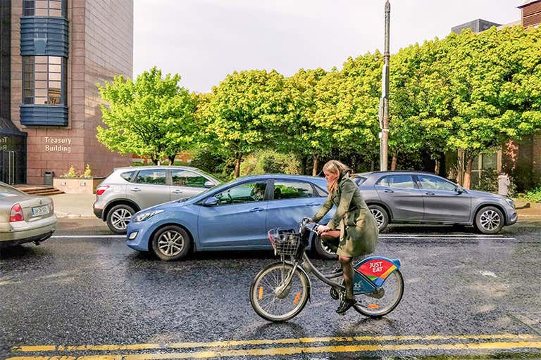 Una persona pasa en bicicleta junto a un coche en una calle de Dublín.