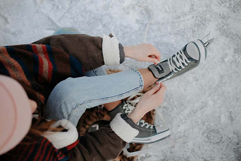 Person lacing up ice skates on a snowy surface in Berlin.