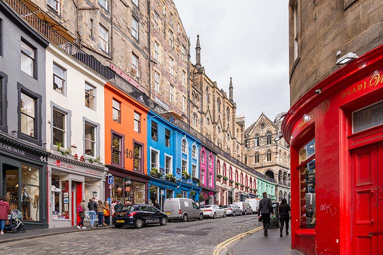 A vibrant street in Edinburgh with colorful buildings and people walking.