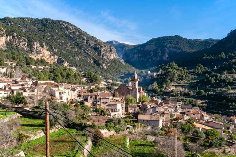 A scenic view of the village of Valldemossa in Mallorca, surrounded by mountains and greenery.