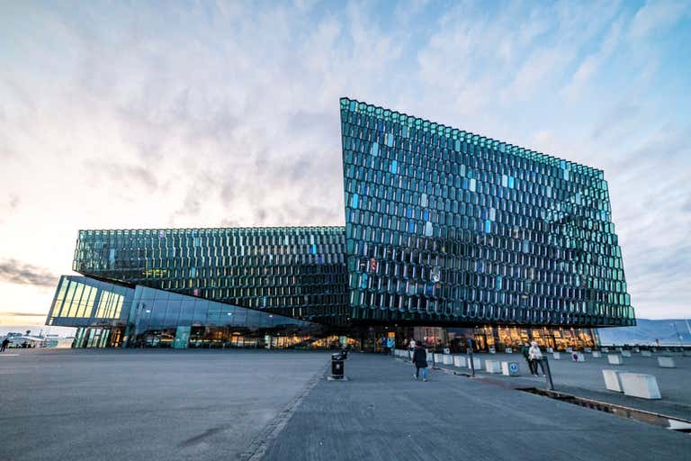 Moderno edificio de cristal en Reikiavik con un cielo nublado de fondo.