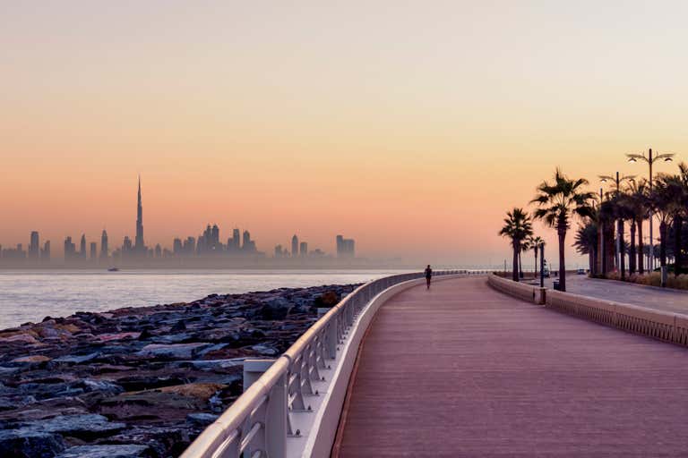 A serene sunrise over Dubai's skyline as seen from Palm Jumeirah Boardwalk.