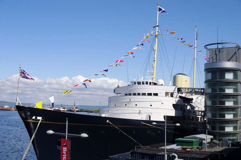 The Royal Yacht Britannia docked at a port with flags flying