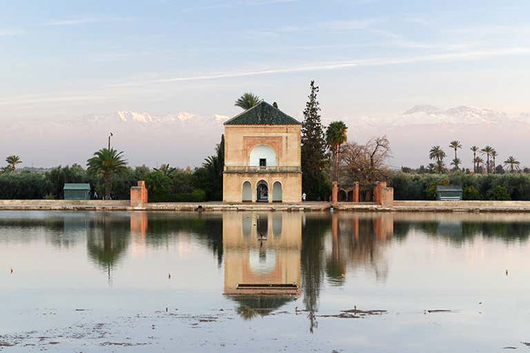Una vista serena de los Jardines Menara con las montañas del Atlas al fondo.