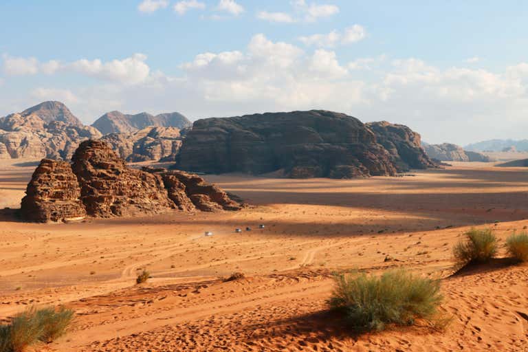 Rocky formations under a partly cloudy sky in the Wadi Rum Desert.
