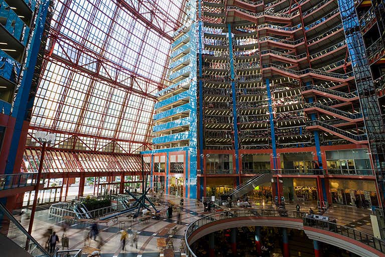 Interior de un atrio de varios pisos con coloridos elementos estructurales que incluyen vigas de acero rojas y azules, techo de cristal y múltiples niveles visibles en este edificio de Chicago.