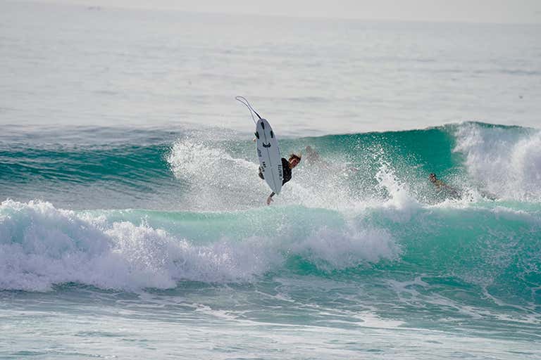 Un surfista coge aire sobre una ola turquesa frente a la costa de Agadir.