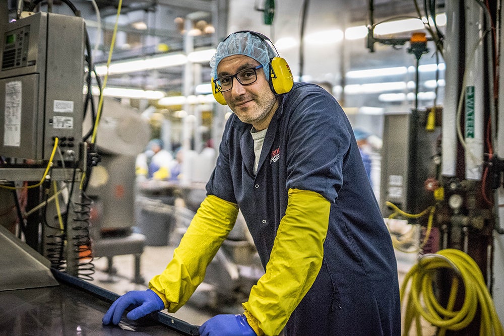 A Trident Seafoods employee wearing safety goggles and ear protection while standing on the processing line