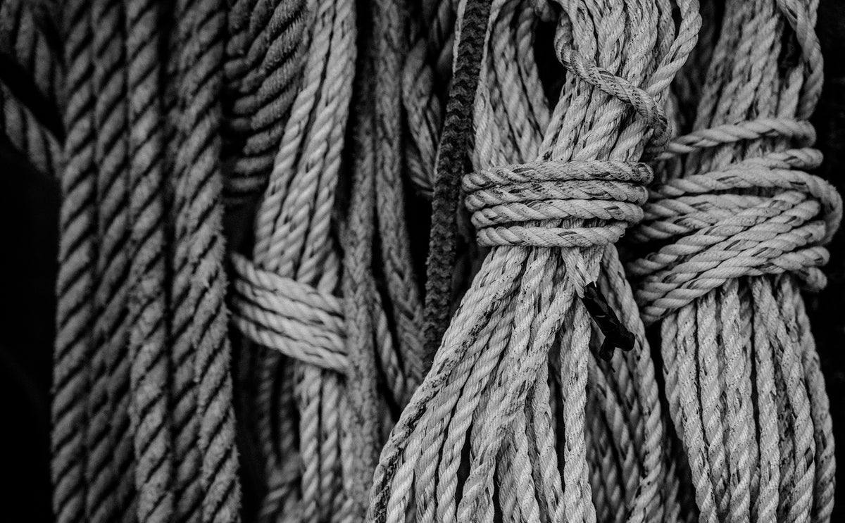 A bundle of fishing rope hangs from a fishing vessel