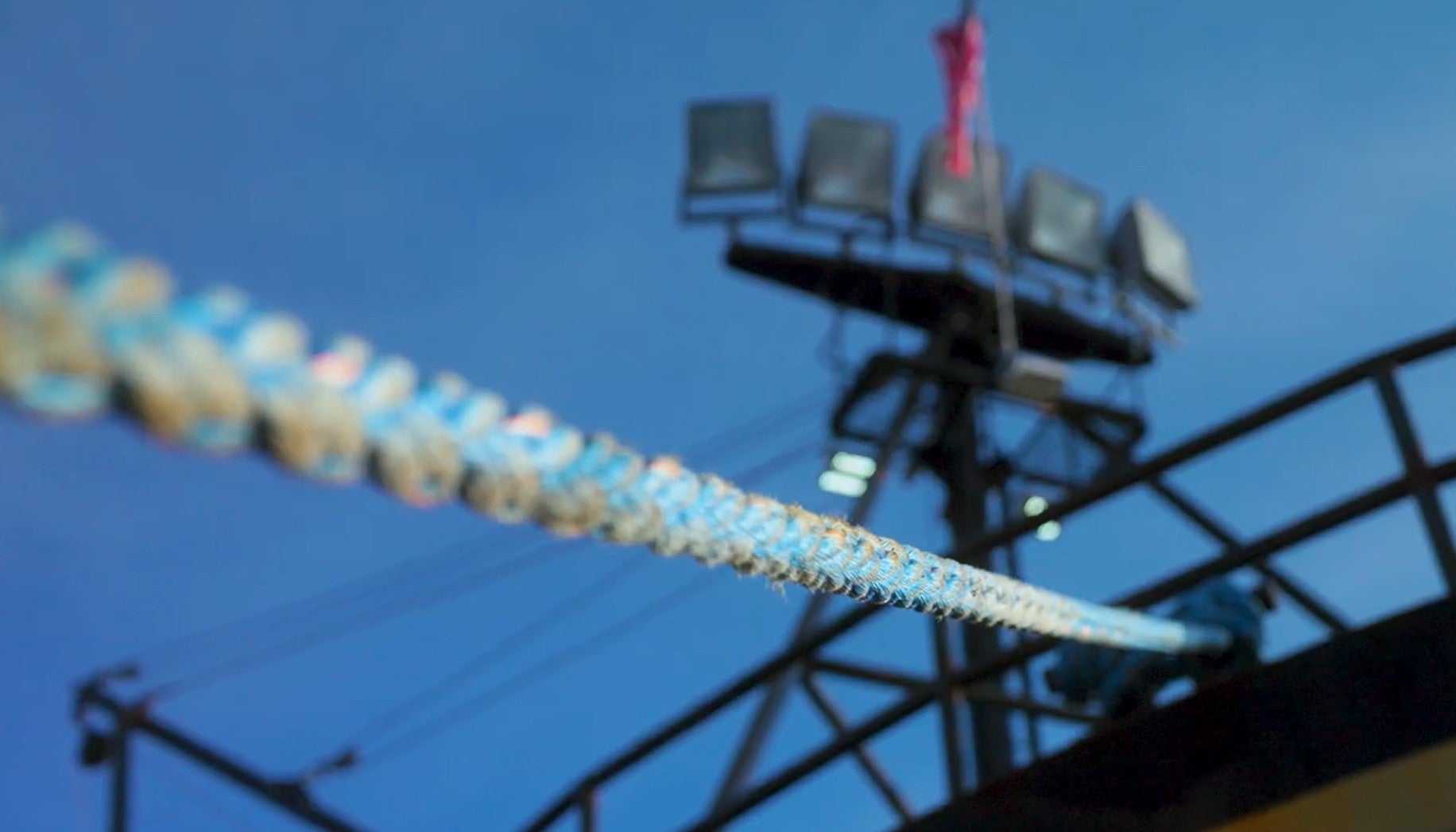 A rope stretches towards blurred lights on a commercial fishing vessel against a clear sky