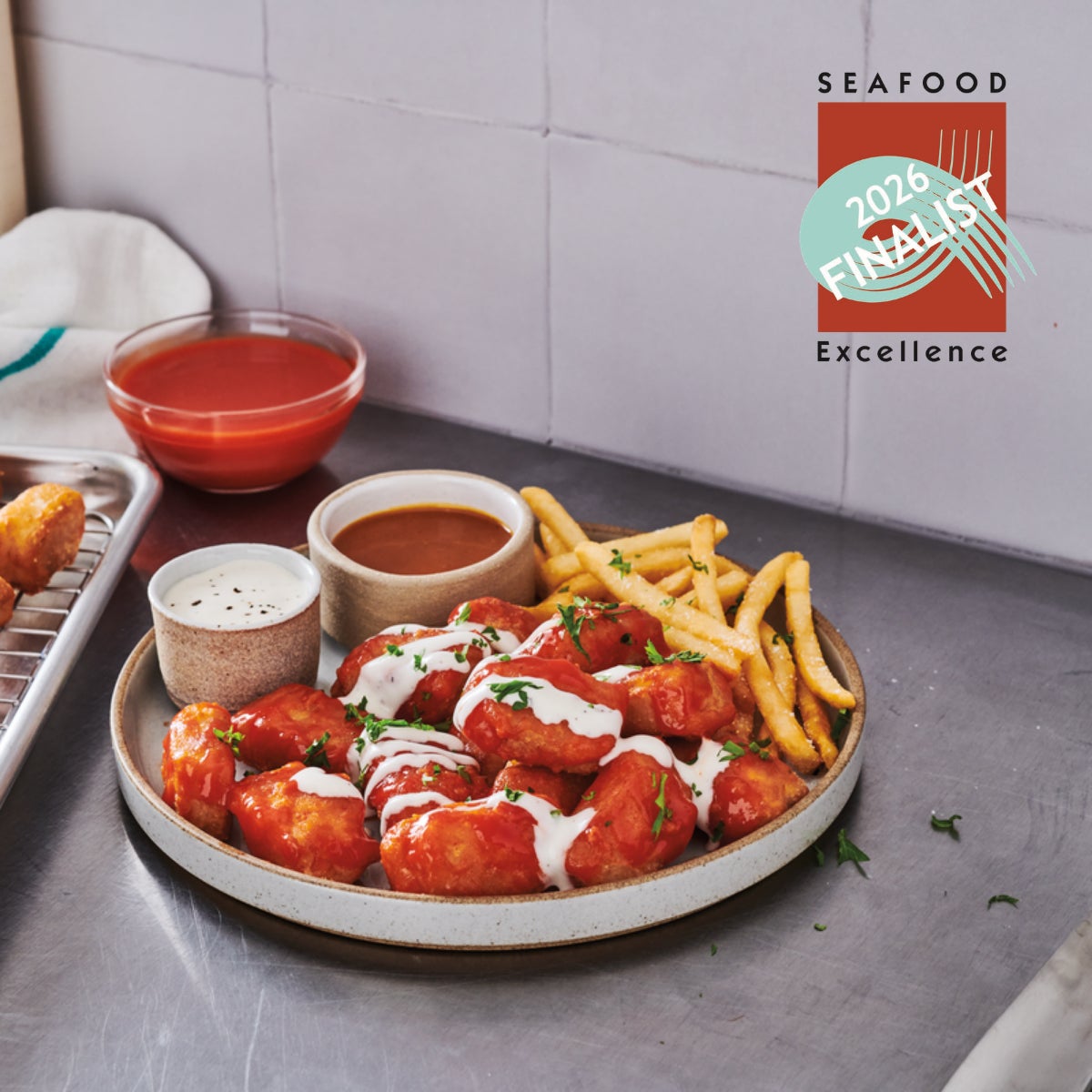 Trident's Crispy Battered Sauceable Nuggets sit on a hot plate in a commercial kitchen against a backdrop of white tile