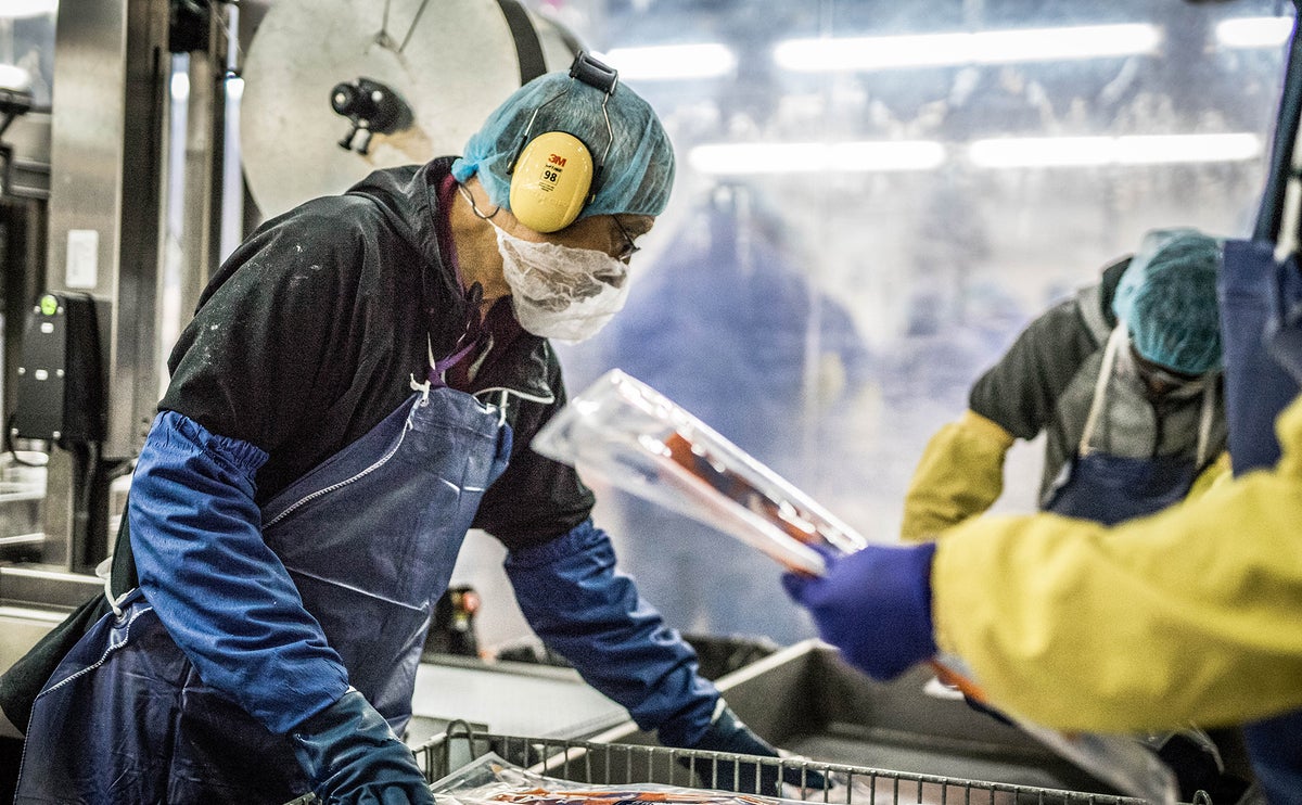 A Trident Seafoods employee wearing ear protection packages wild Alaska salmon fillets. 