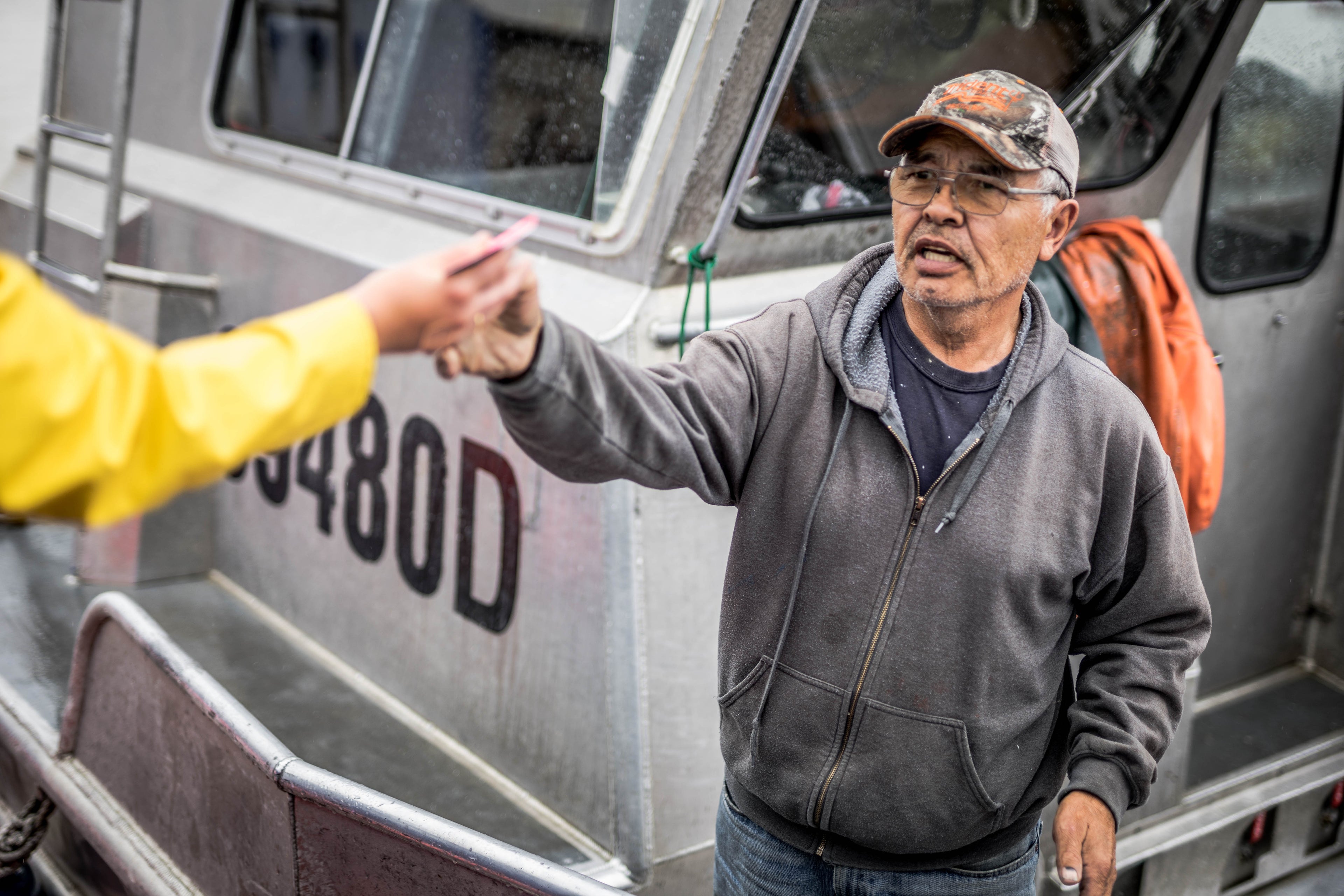 Man reaching out to another person standing on a boat. 