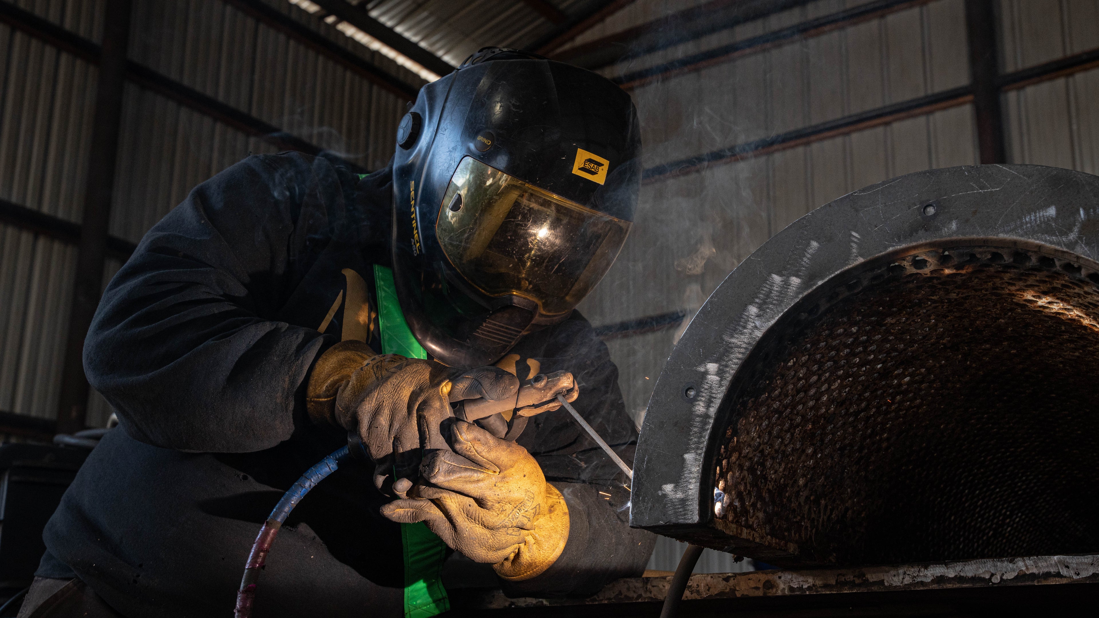 Skilled trades worker welding a curved metal component inside an industrial facility at Trident Seafoods