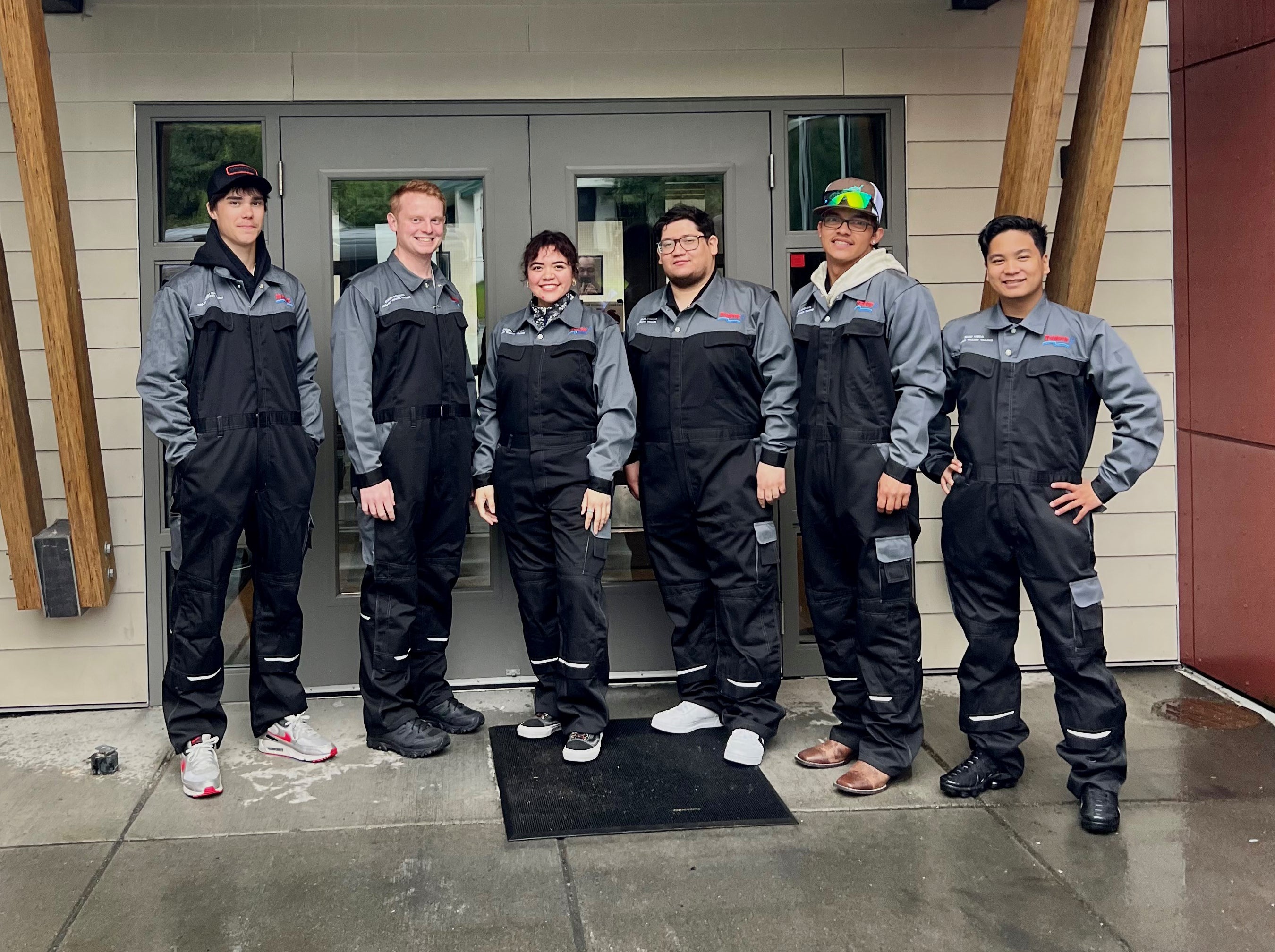 Six employees from Trident's Skilled Trades Trainee Program stand shoulder to shoulder