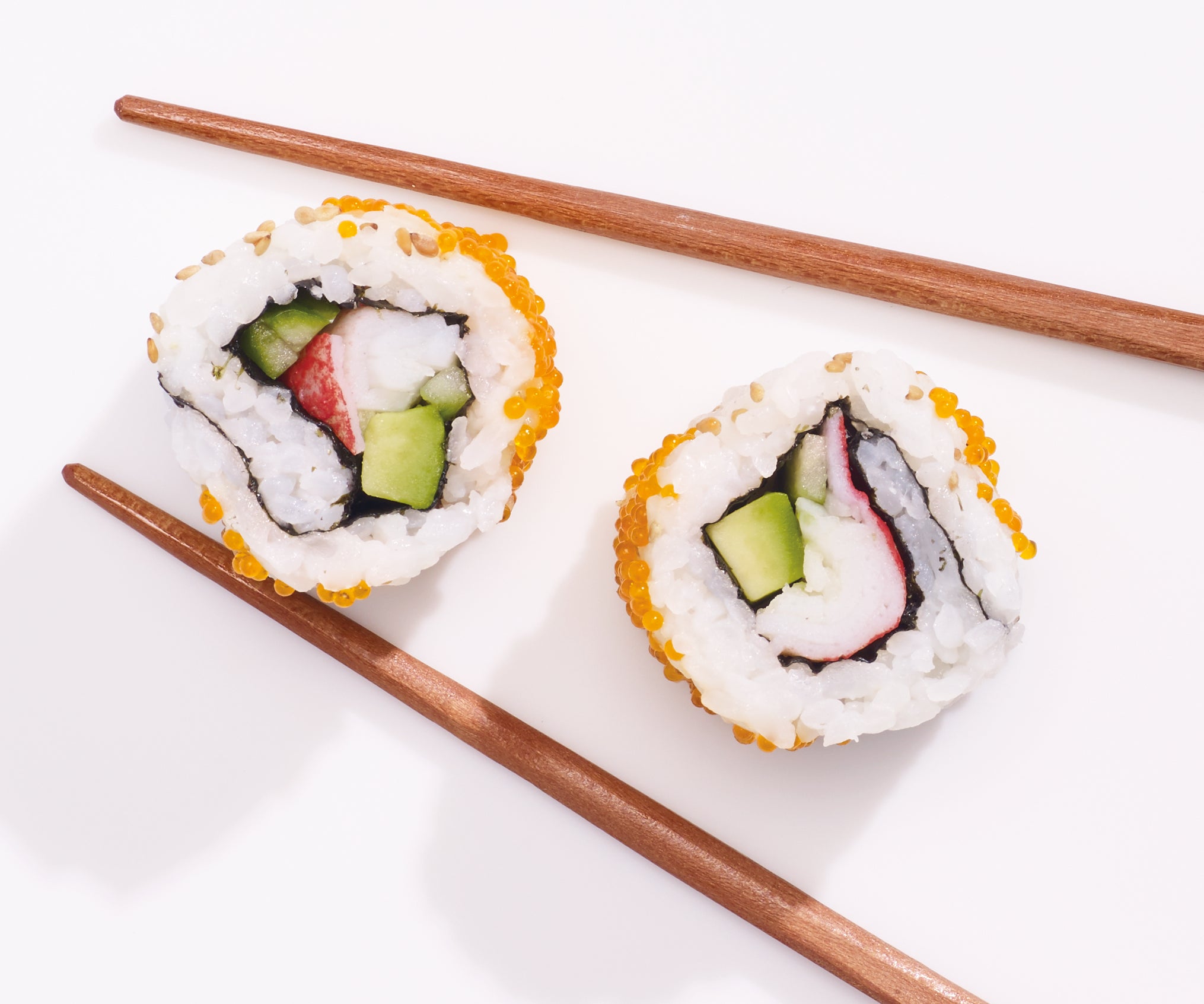 two pieces of a Sushi roll with chopsticks  