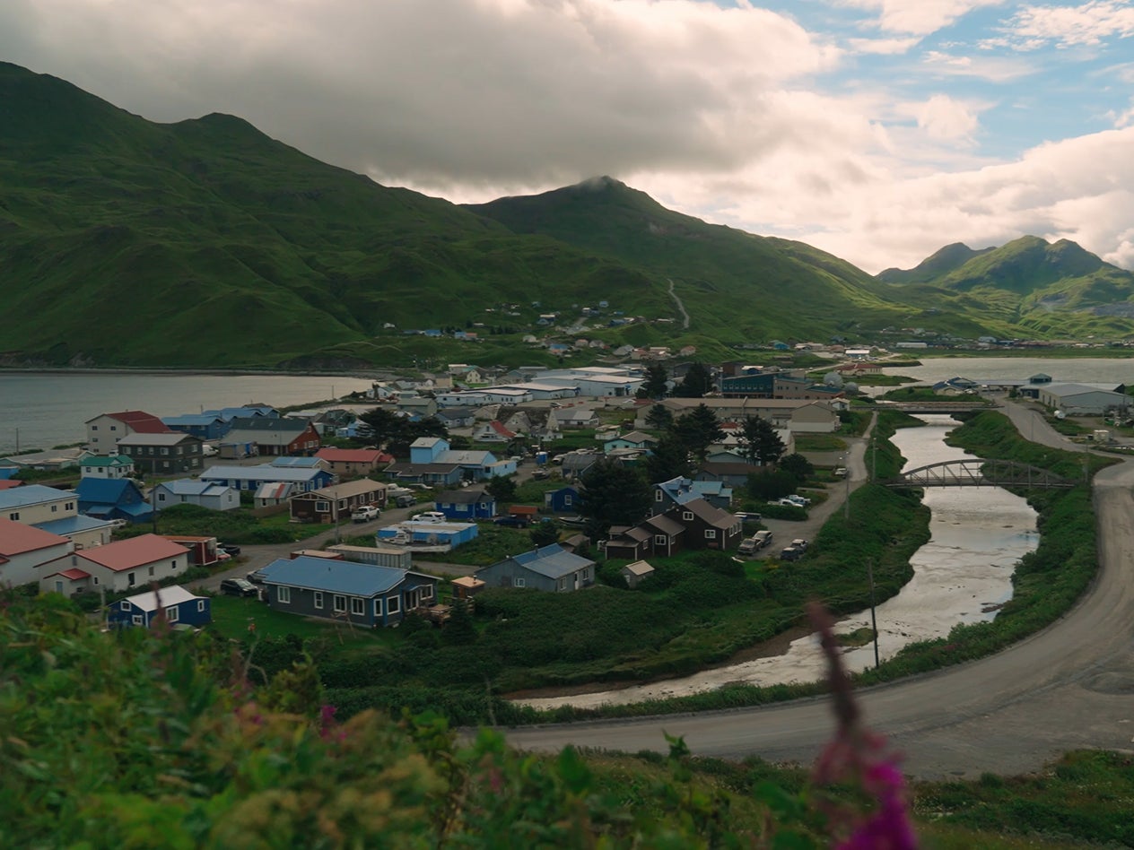 A small coastal town in Alaska nestled between green mountains and a bay
