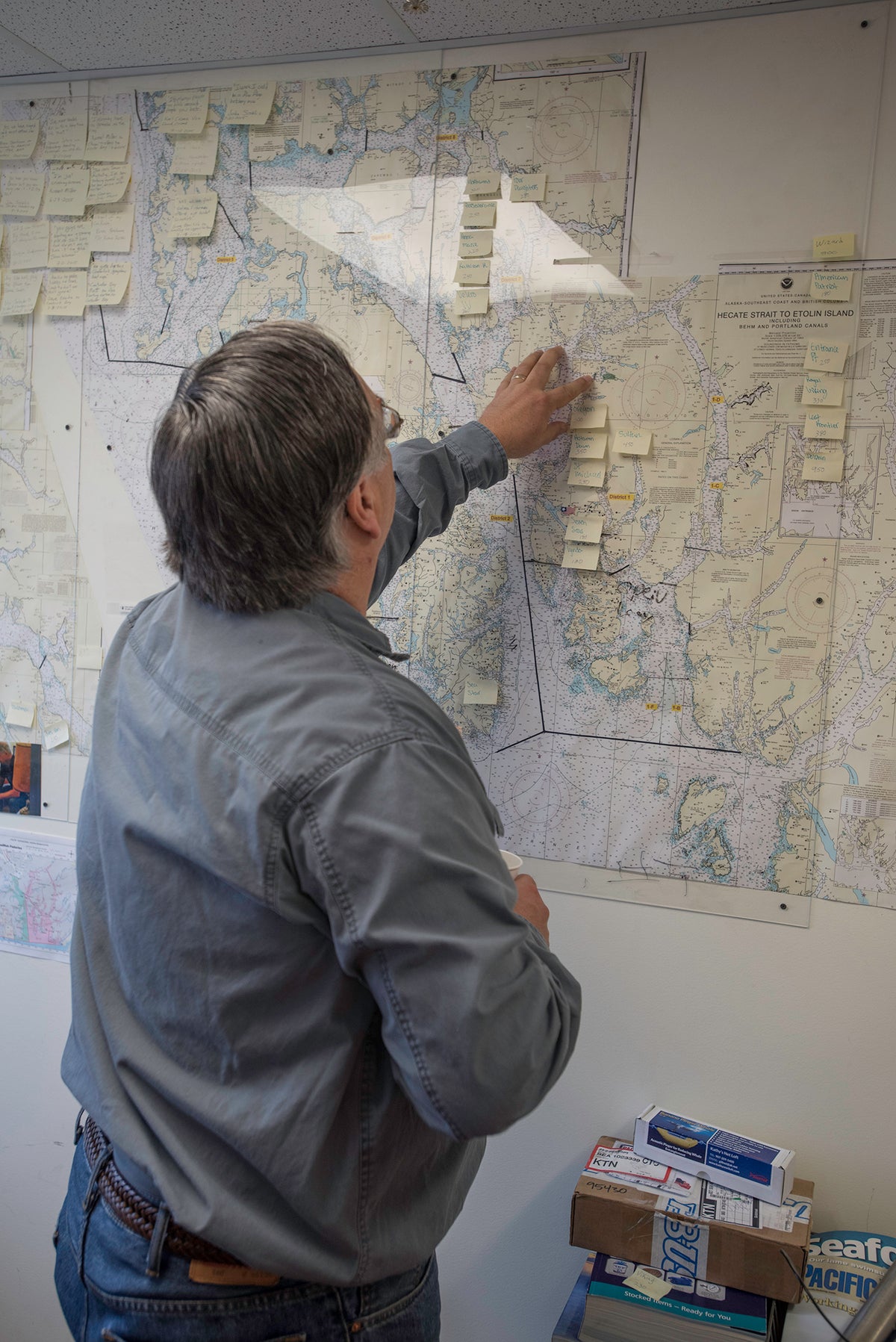 Man standing, looking at map in an office