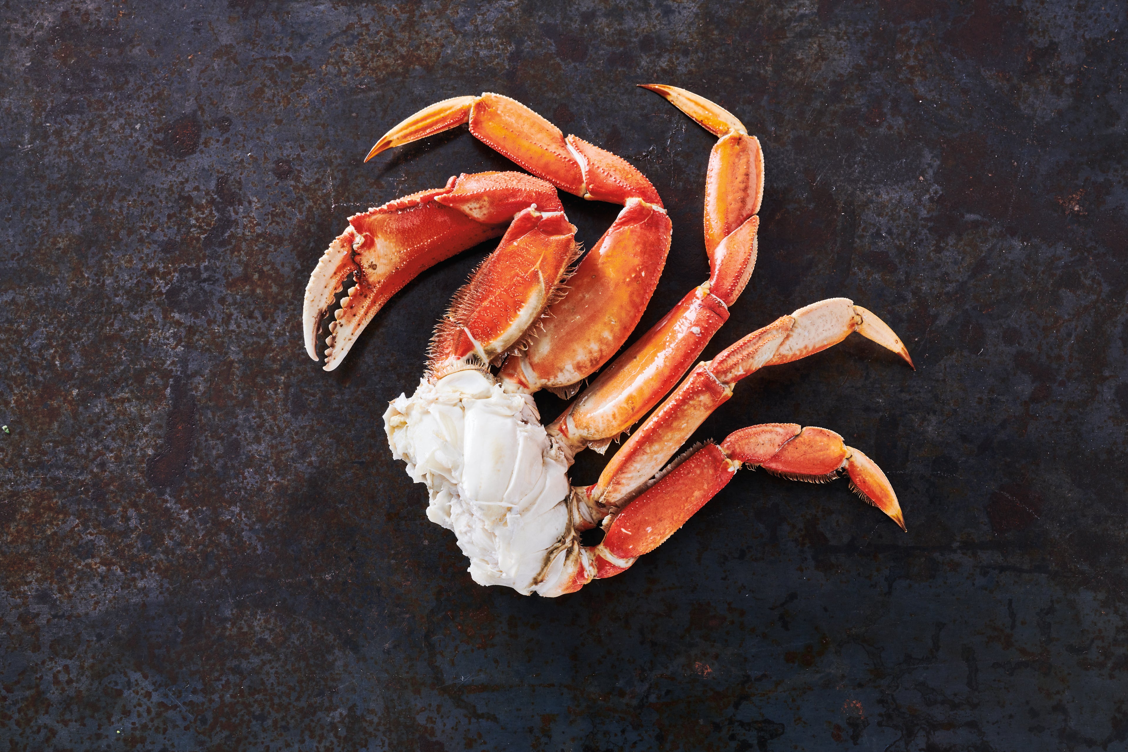 Wild Alaska Dungeness crab section laid out with a black metal background