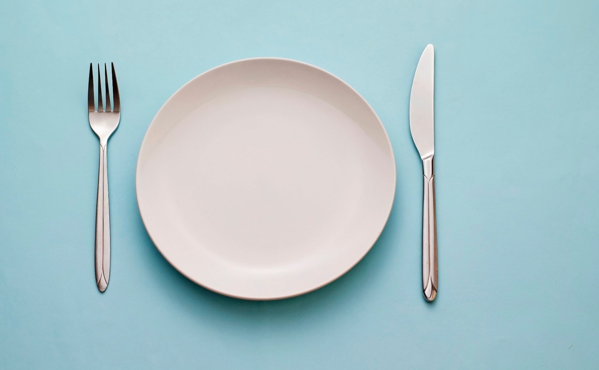 An empty plate sits next to a fork and knife