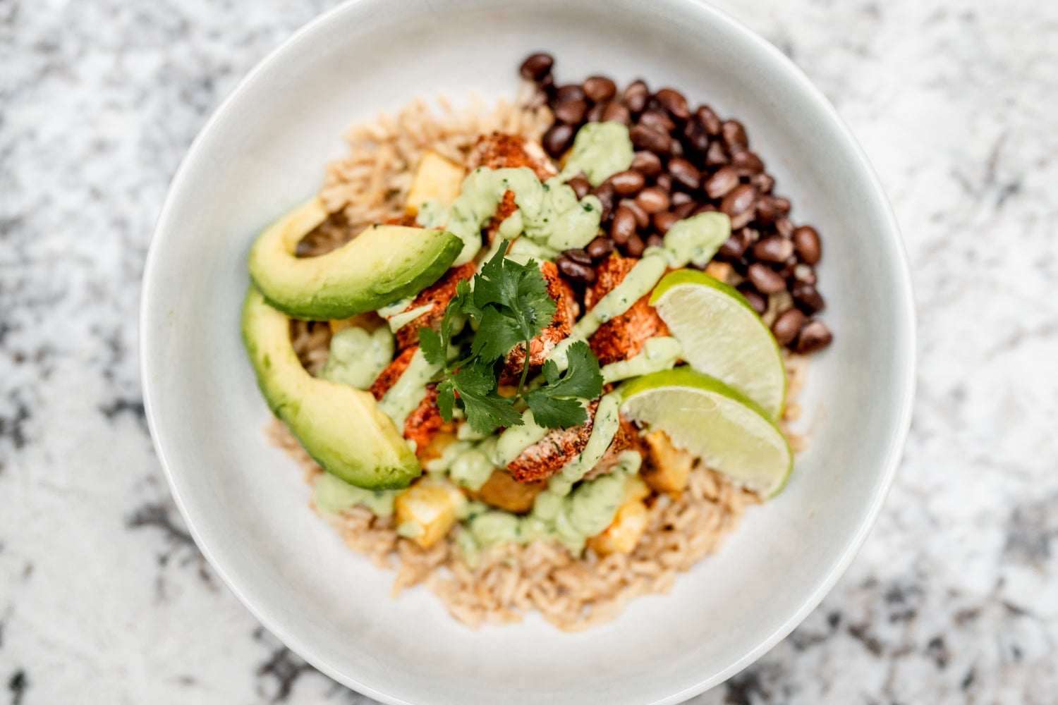 Wild Alaska salmon sits atop a bed of rice in this salmon and sweet potato bowl slide 0