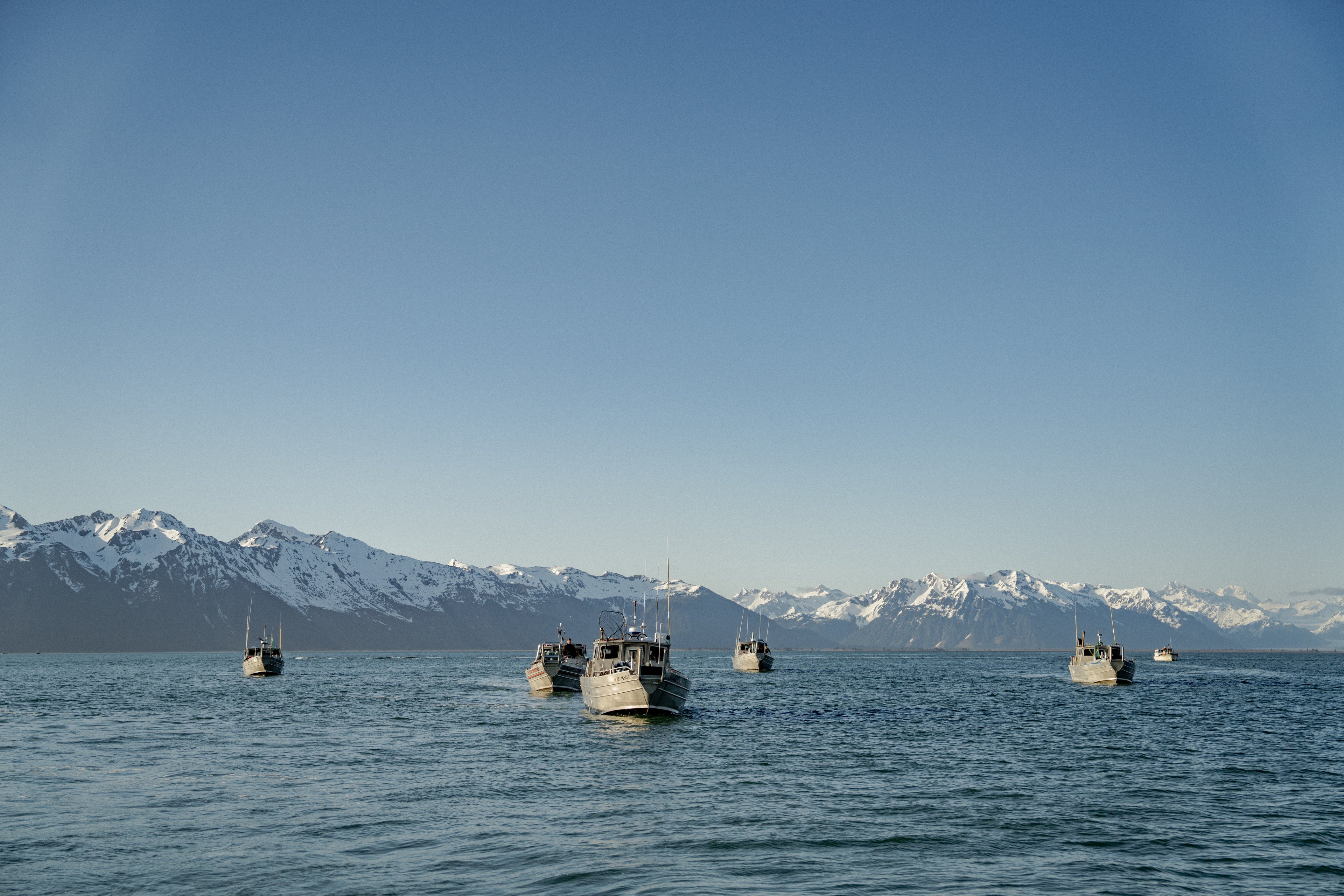 Drift boats on the water with mountains in the background