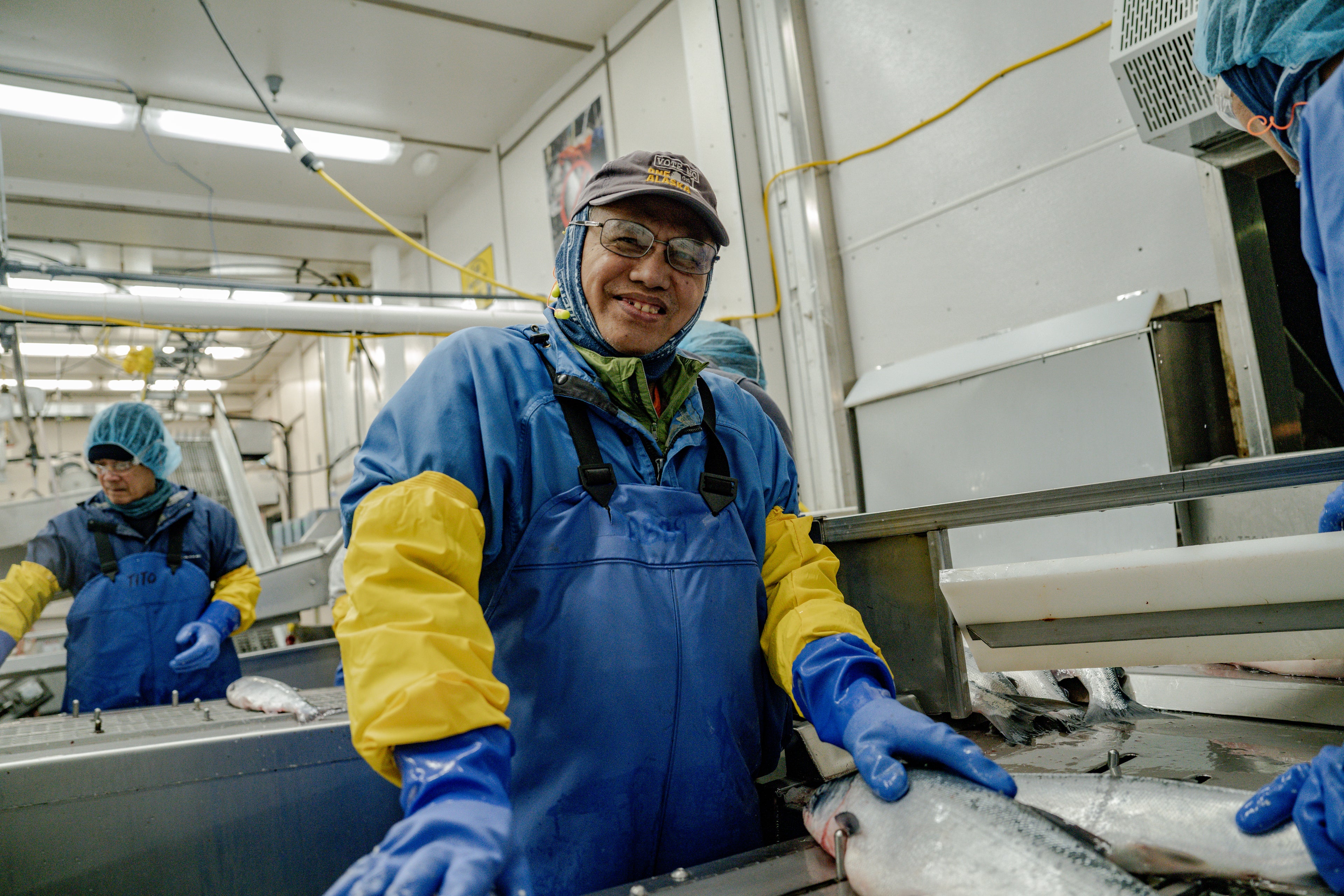 Worker in a fish plant smiling at the camera on the fish sorting line. 
