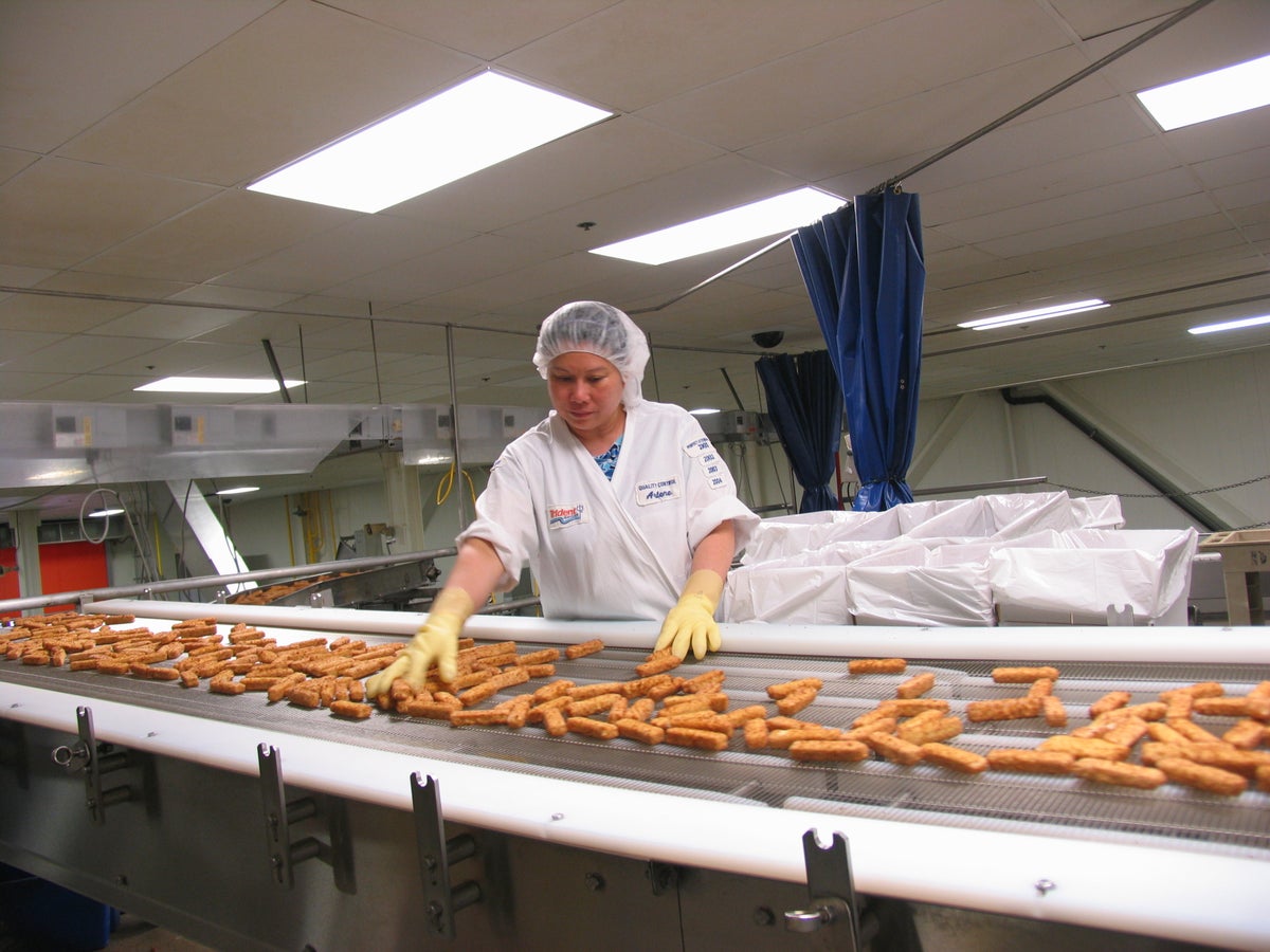 person working on the fish stick conveyor belt