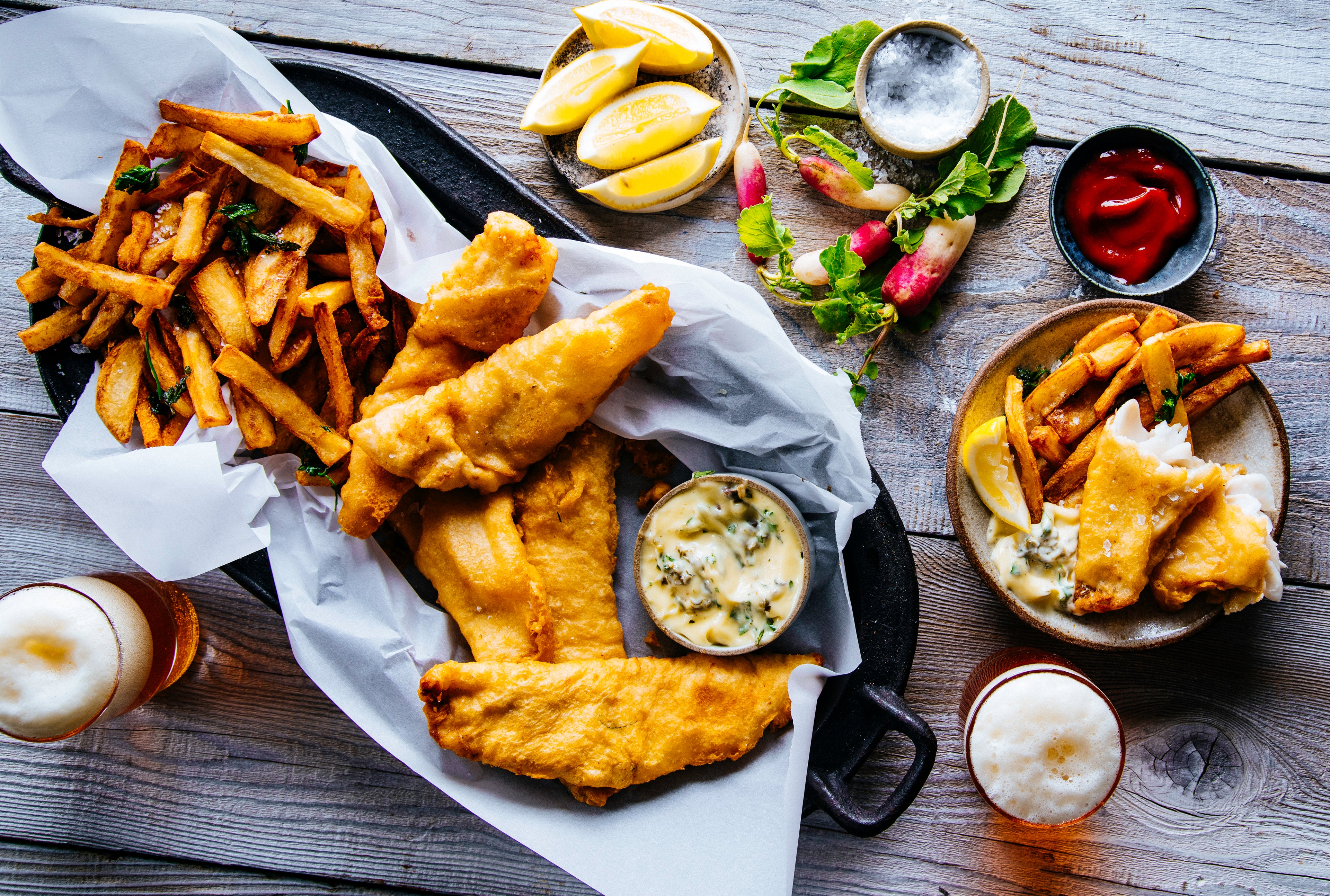 Beer batter Alaska pollock with French fries and accoutrements. Photographed overhead. 