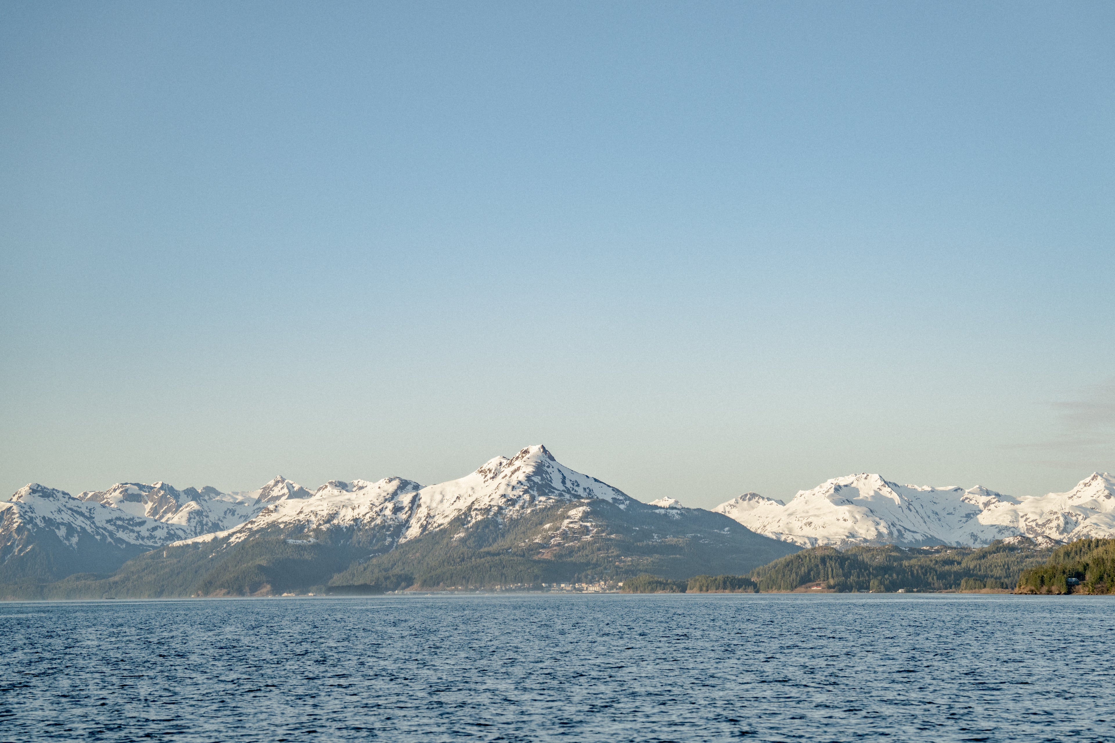 Landscape with mountains covered in snow and ocean in the front