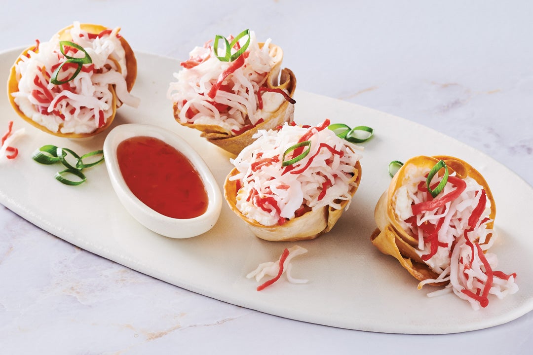 Crab Rangoon bites plated with sweet chili sauce in a cup. 